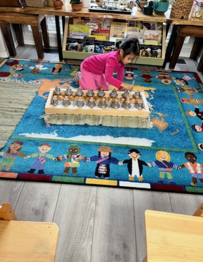 Coronation Montessori young girl on carpet with game